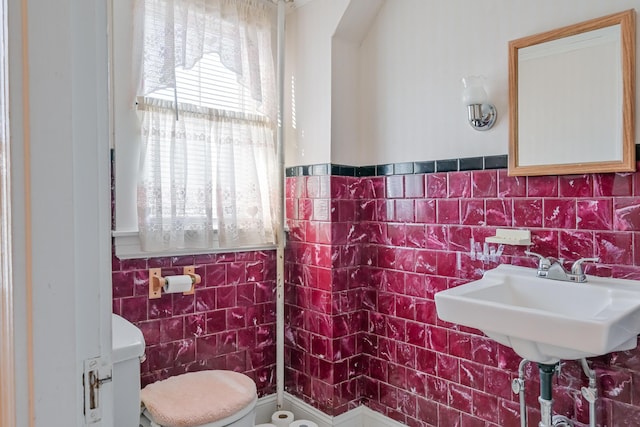 bathroom featuring sink, toilet, and tile walls