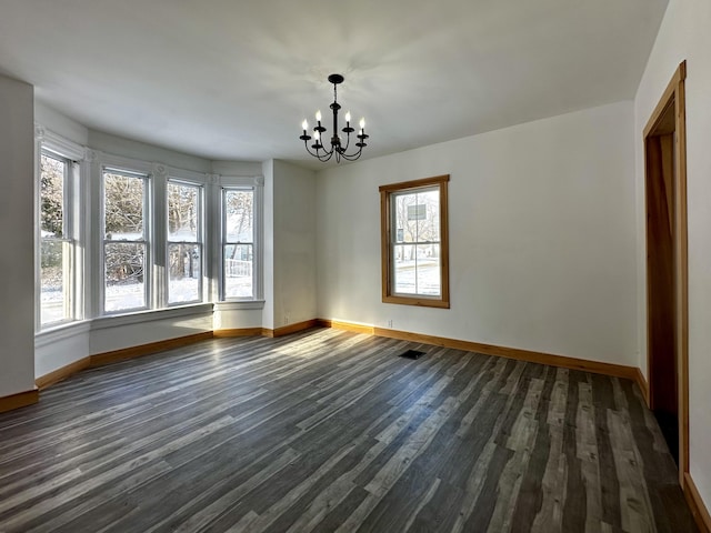 unfurnished dining area with plenty of natural light, dark wood-type flooring, and a notable chandelier