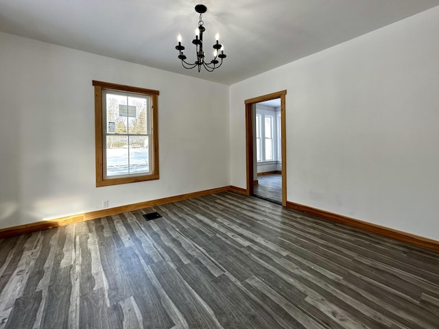 empty room featuring dark wood-type flooring and a chandelier