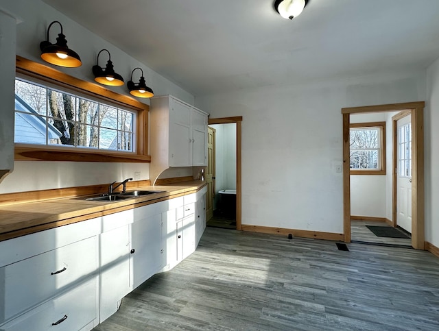 kitchen with white cabinets, light hardwood / wood-style flooring, and sink