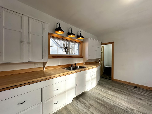 kitchen featuring white cabinetry, sink, and light wood-type flooring