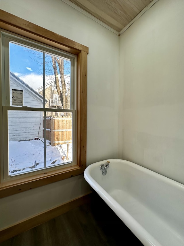 bathroom with crown molding, a washtub, and hardwood / wood-style floors