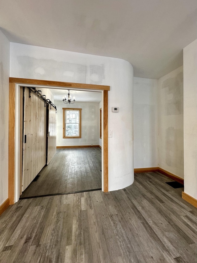 empty room featuring dark wood-type flooring and a notable chandelier