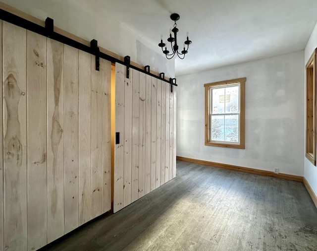 spare room with dark hardwood / wood-style flooring and a barn door