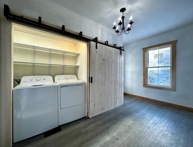 washroom with dark hardwood / wood-style floors, a barn door, washing machine and dryer, and an inviting chandelier