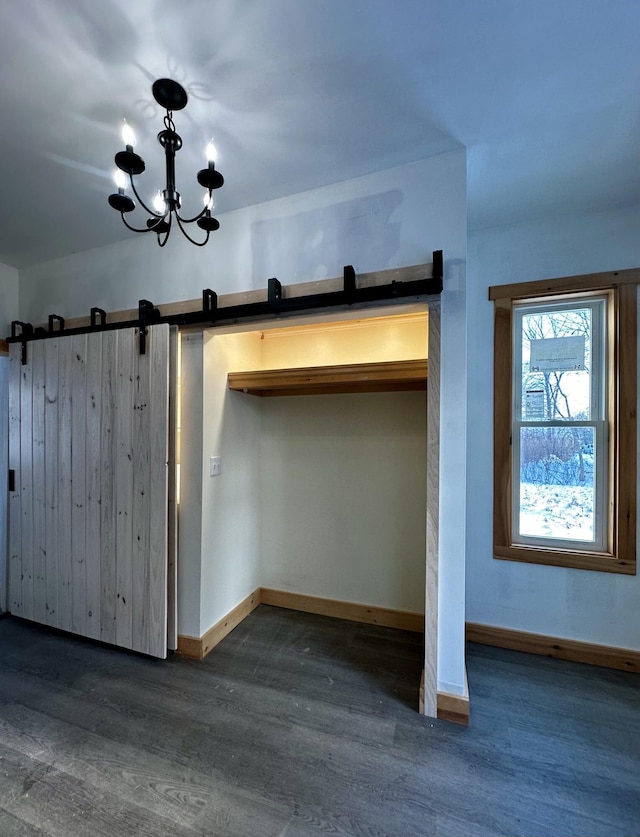 room details featuring a barn door, hardwood / wood-style flooring, and a notable chandelier