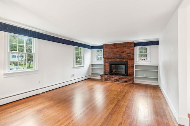 unfurnished living room with hardwood / wood-style flooring, a healthy amount of sunlight, a fireplace, and a baseboard radiator