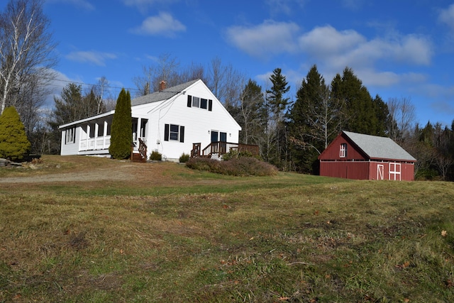 view of side of property featuring a lawn and an outbuilding