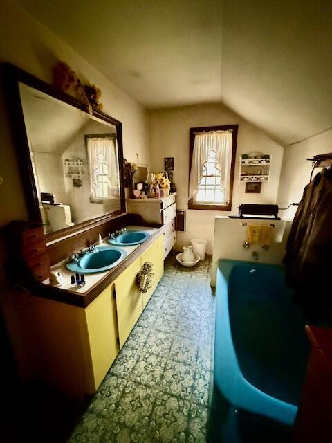 bathroom featuring a bathing tub, vanity, and vaulted ceiling