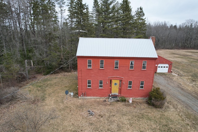 21 Talmadge Rd, Talmadge, ME 04492 - view of front of house featuring driveway, an outdoor structure, a forest view, a detached garage, and metal roof
