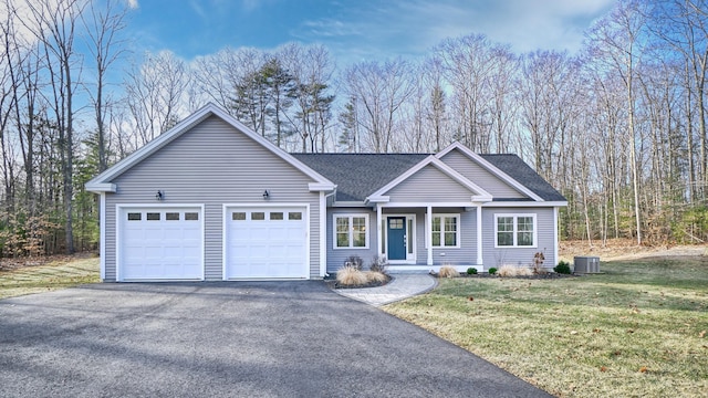 ranch-style house featuring a front lawn, central AC unit, and a garage