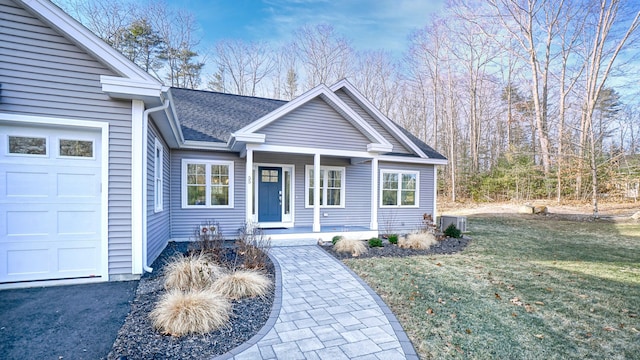 view of front of property with covered porch, a garage, a front lawn, and central air condition unit