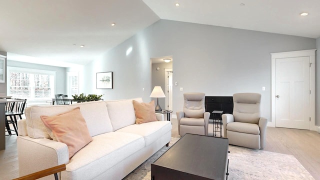 living room with light wood-type flooring and vaulted ceiling