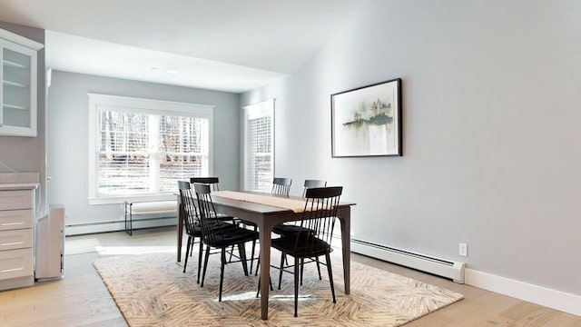 dining space with light hardwood / wood-style flooring and a baseboard heating unit