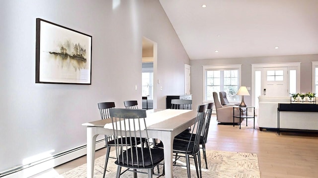 dining space with light hardwood / wood-style flooring, a baseboard radiator, and vaulted ceiling