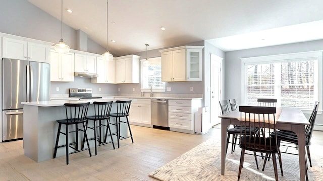 kitchen featuring pendant lighting, a center island, stainless steel appliances, and white cabinetry