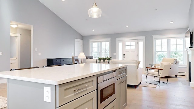 kitchen featuring a center island, a baseboard heating unit, light hardwood / wood-style floors, pendant lighting, and lofted ceiling