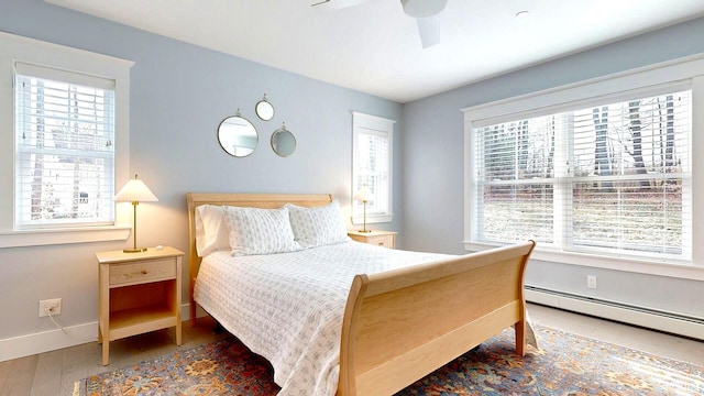 bedroom with ceiling fan, a baseboard radiator, and wood-type flooring