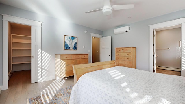 bedroom featuring a wall mounted air conditioner, a walk in closet, ceiling fan, a baseboard heating unit, and a closet