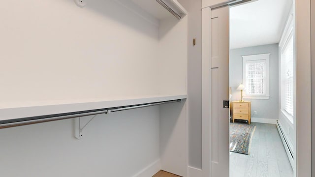 spacious closet featuring hardwood / wood-style flooring and baseboard heating