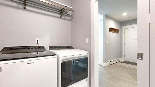 washroom with light hardwood / wood-style floors, a baseboard radiator, and washer and clothes dryer