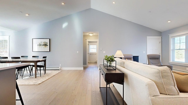 living room featuring plenty of natural light, a baseboard radiator, lofted ceiling, and light wood-type flooring