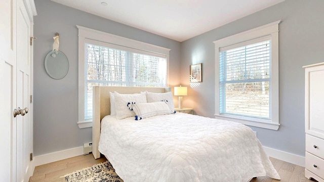 bedroom with light wood-type flooring and a baseboard heating unit