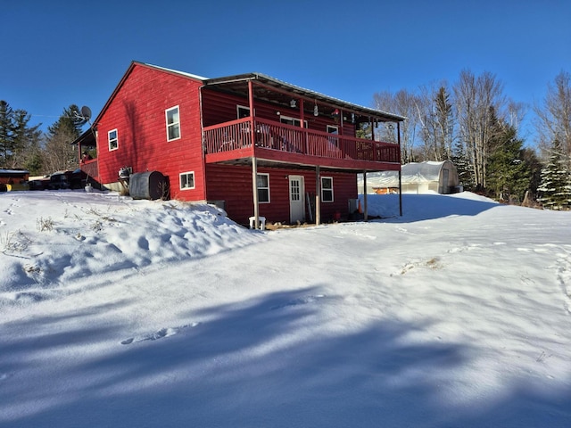 snow covered rear of property featuring an outbuilding and a wooden deck