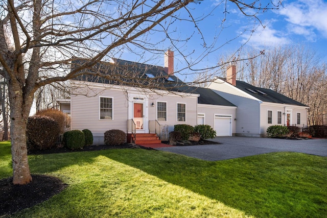 view of front of property with a garage, driveway, a chimney, and a front lawn