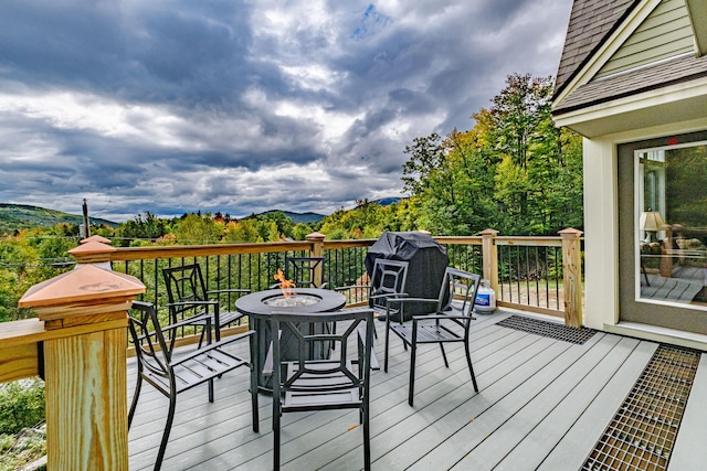 wooden deck with a mountain view, a grill, and an outdoor fire pit