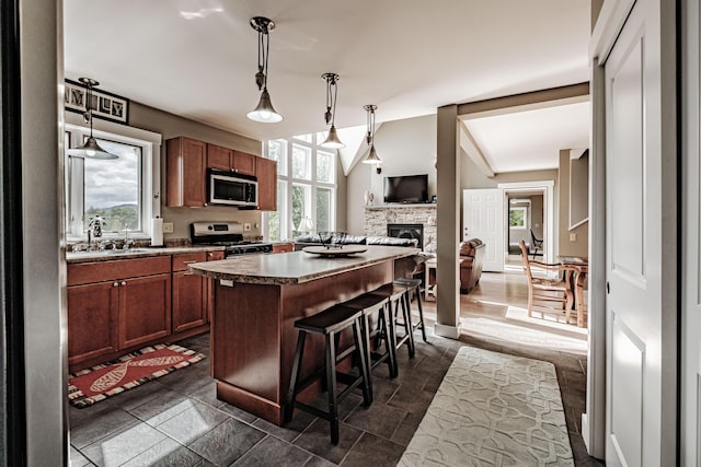 kitchen with a kitchen breakfast bar, stainless steel appliances, a kitchen island, and hanging light fixtures