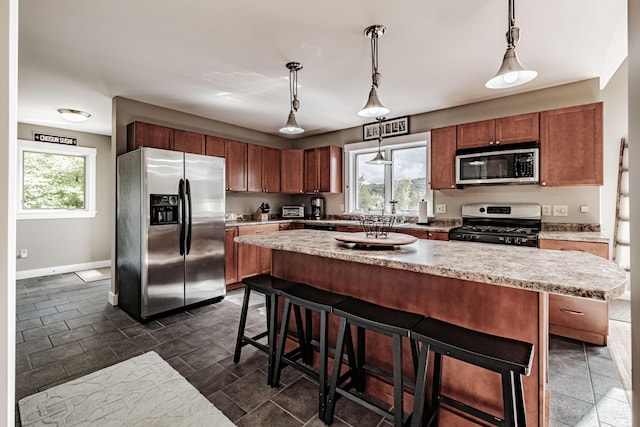 kitchen with a breakfast bar, hanging light fixtures, a center island, and stainless steel appliances