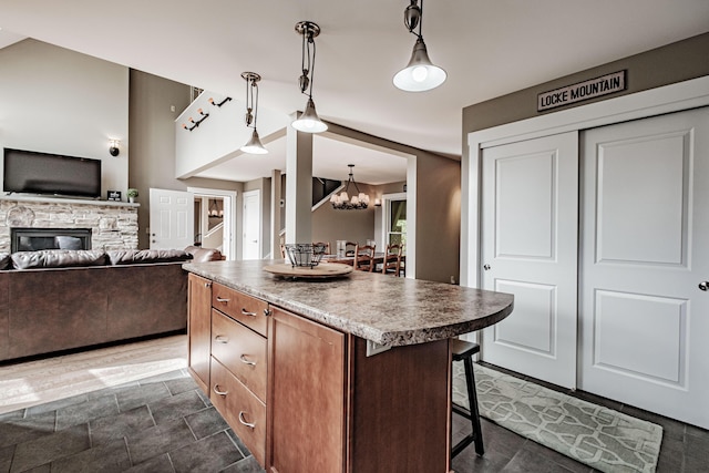 kitchen featuring a breakfast bar, an inviting chandelier, a fireplace, a center island, and hanging light fixtures