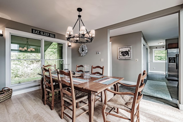 dining room with light hardwood / wood-style flooring, an inviting chandelier, and a wealth of natural light