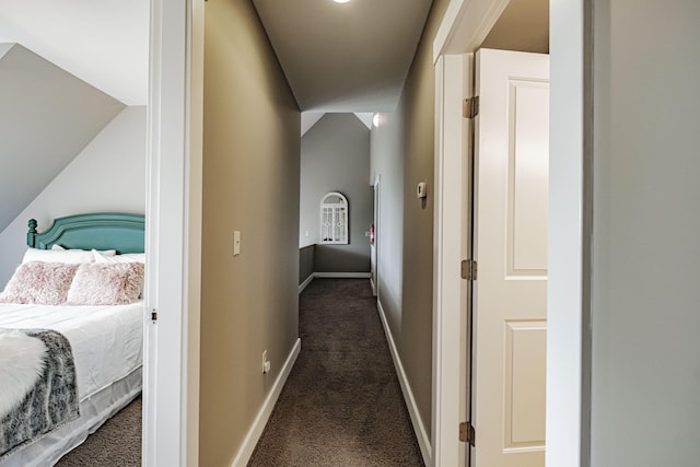 hallway featuring dark carpet and lofted ceiling