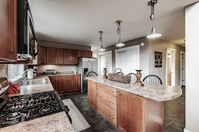 kitchen featuring stainless steel appliances, sink, pendant lighting, a center island, and a breakfast bar area