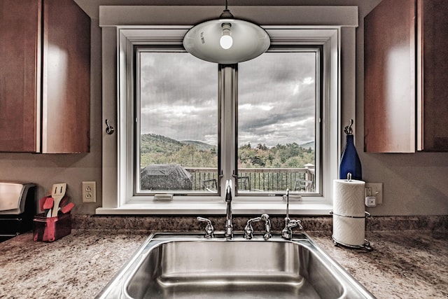 kitchen with a mountain view, decorative light fixtures, dark stone countertops, and sink