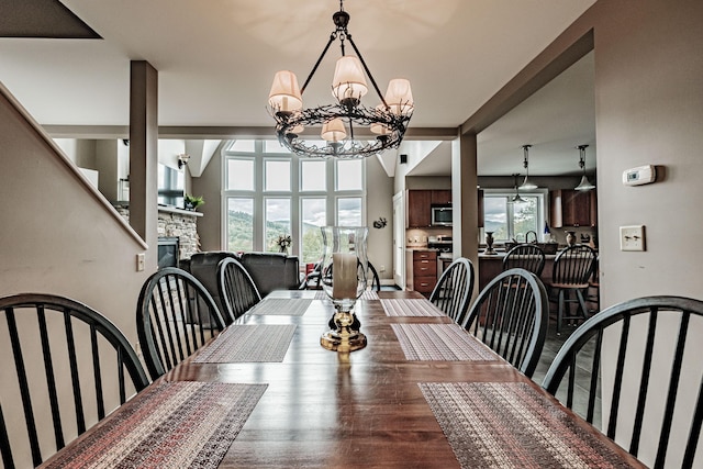 dining room featuring a chandelier, a stone fireplace, and plenty of natural light