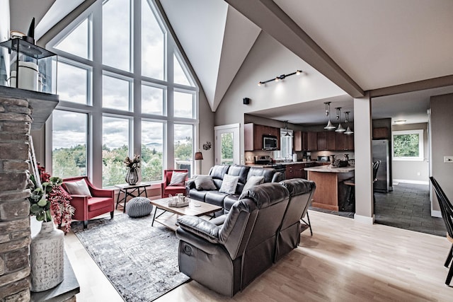 living room featuring beamed ceiling, light hardwood / wood-style floors, sink, and a high ceiling