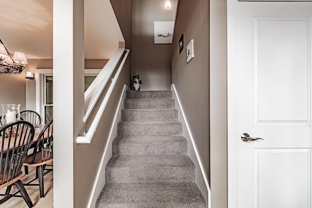 stairs featuring a notable chandelier