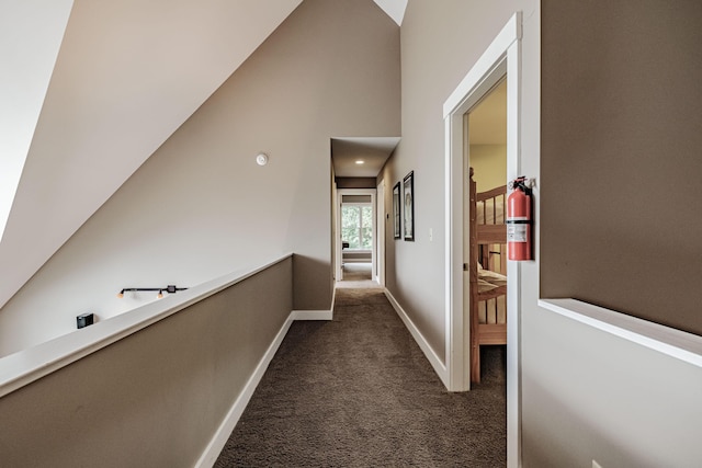 hall featuring dark colored carpet and vaulted ceiling