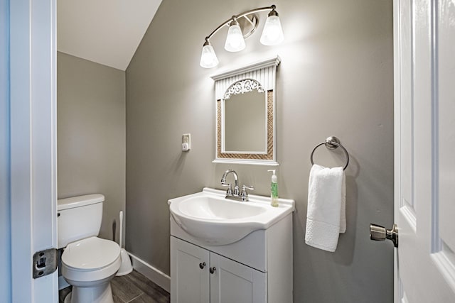 bathroom featuring vanity, toilet, and lofted ceiling