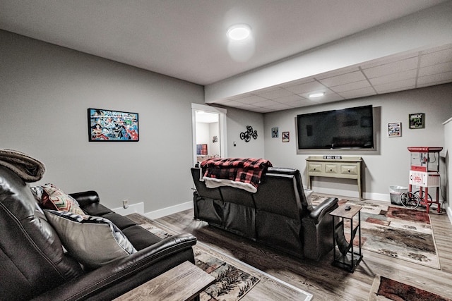 living room featuring wood-type flooring and a drop ceiling