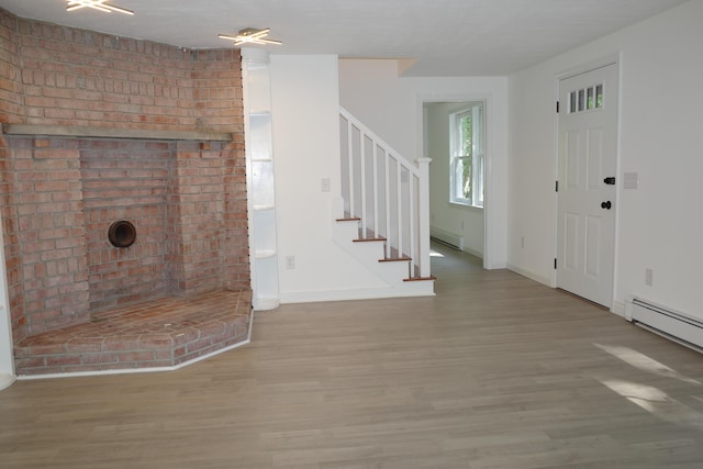 unfurnished living room with a baseboard heating unit and hardwood / wood-style flooring