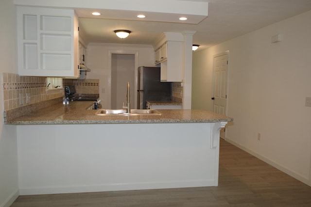 kitchen featuring white cabinetry, kitchen peninsula, stainless steel refrigerator, and black / electric stove