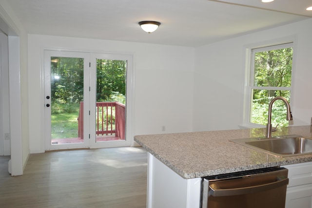 kitchen featuring sink, white cabinets, stainless steel dishwasher, and light wood-type flooring