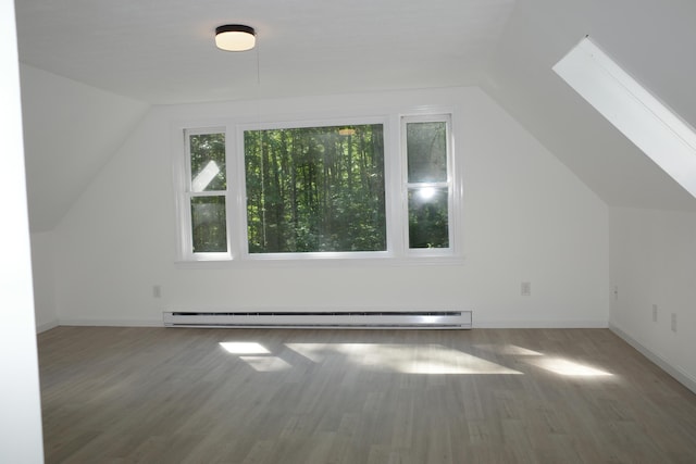 additional living space featuring hardwood / wood-style flooring, lofted ceiling with skylight, and baseboard heating