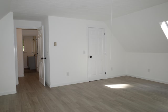 additional living space with vaulted ceiling and light hardwood / wood-style flooring