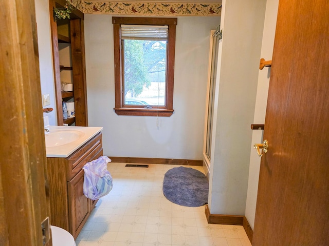 bathroom featuring a shower with door and vanity