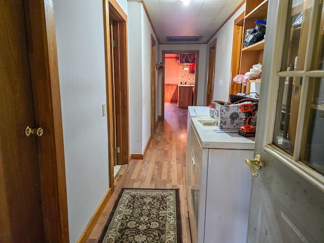 corridor with light hardwood / wood-style floors and ornamental molding